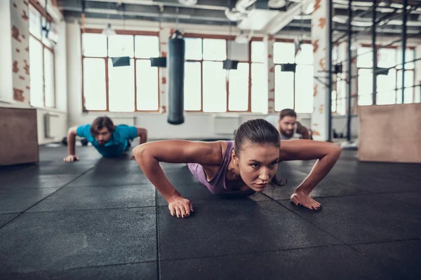 Erkek ve kadının yapması Push Ups. Training Day. Fitness Kulübü. Sağlıklı bir yaşam tarzı. Güçlü atlet. Aktif tatiller. CrossFit kavramı. Parlak spor salonu. Rahat spor giyim. Triceps kasları.