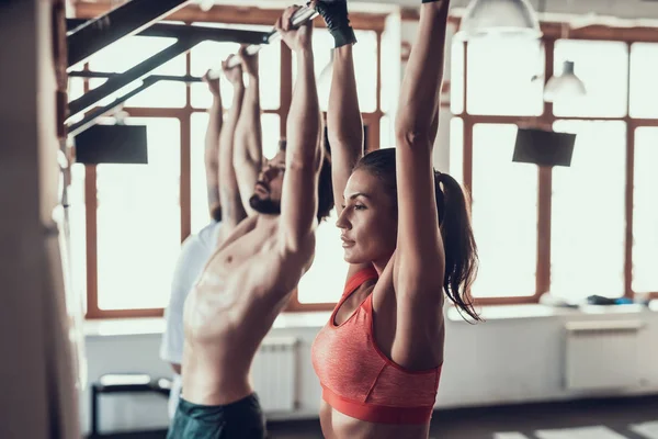 Two Guys And Girl Are Doing Pull Ups In The Gym. Training Day. Fitness Club. Healthy Lifestyle. Powerful Athlete. Active Holidays. Crossfit Concept. Horizontal Bar. Back Muscles. Spine Training. — Stock Image Two Guys Girl Doing Pull Ups Gym Training Day Fitness Royalty Free Stock Photos
