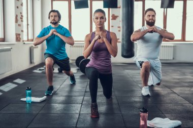 Kız ve iki adam spor salonunda hamle yapıyor. Training Day. Fitness Kulübü. Sağlıklı bir yaşam tarzı. Güçlü atlet. Aktif tatiller. CrossFit kavramı. Rahat spor giyim. Bacak Germe.