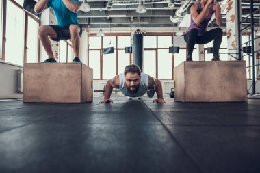 Sportif adam yapıyor iki sporcular arasında Ups itin. Training Day. Fitness Kulübü. Sağlıklı bir yaşam tarzı. Aktif tatiller. CrossFit kavramı. Parlak spor salonu. Rahat spor giyim. Egzersizleri tekrarlayın.