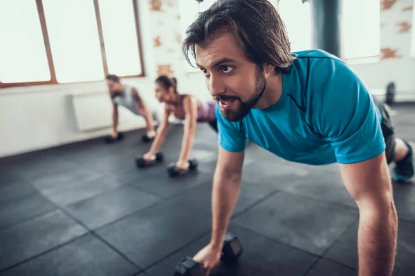 两个男人和女人在哑铃上推 Ups 培训日 健身俱乐部 健康的生活方式 强大的运动员 活动假期 交叉的概念 明亮的健身房 舒适的运动装 — 图库照片