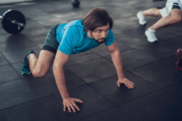 穿蓝色 T恤的运动男在健身房地板上爬行 培训日 健身俱乐部 健康的生活方式 强大的运动员 活动假期 交叉的概念 舒适的运动装 男性力量 — 图库照片