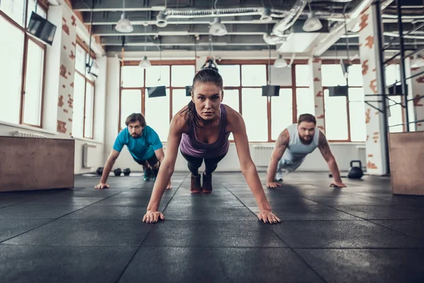 Erkek ve kadının yapması Push Ups. Training Day. Fitness Kulübü. Sağlıklı bir yaşam tarzı. Güçlü atlet. Aktif tatiller. CrossFit kavramı. Parlak spor salonu. Rahat spor giyim. Triceps kasları.