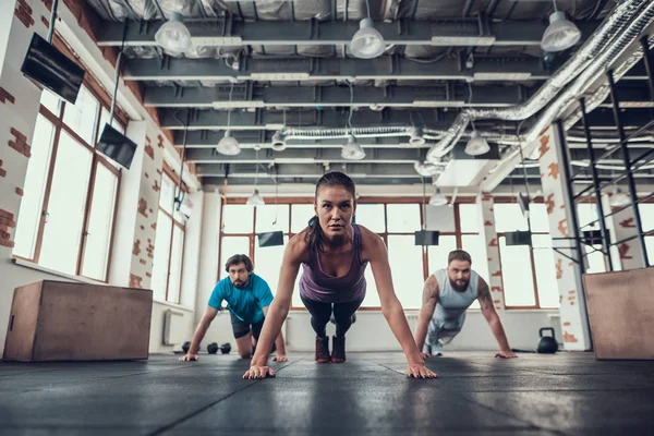 Erkek ve kadının yapması Push Ups. Training Day. Fitness Kulübü. Sağlıklı bir yaşam tarzı. Güçlü atlet. Aktif tatiller. CrossFit kavramı. Parlak spor salonu. Rahat spor giyim. Triceps kasları.
