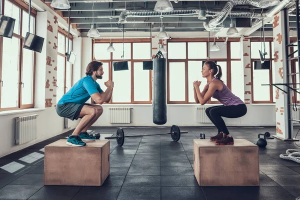 Man And Woman. Squats Exercises. Wood Blocks. Training Day. Fitness Club. Healthy Lifestyle. Powerful Athlete. Active Holidays. Crossfit Concept. Bright Gym. Comfortable Sportswear.