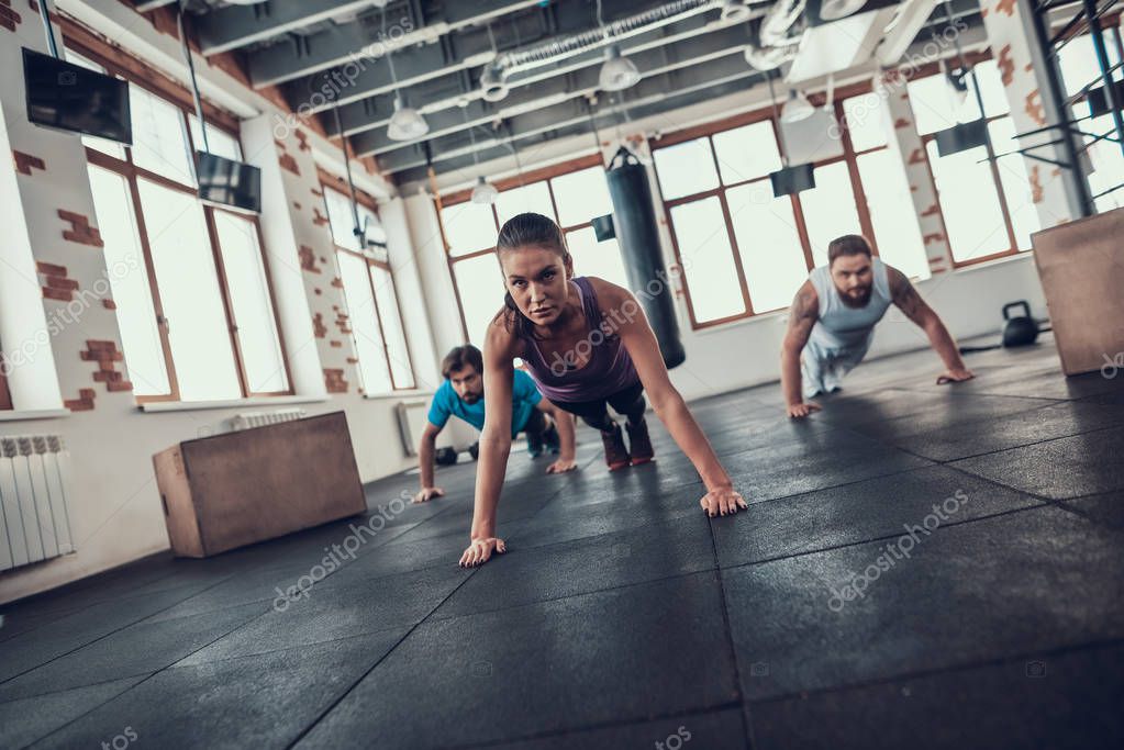Men And Woman Doing Push Ups. Training Day. Fitness Club. Healthy Lifestyle. Powerful Athlete. Active Holidays. Crossfit Concept. Bright Gym. Comfortable Sportswear. Triceps Muscles.