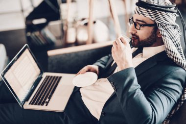 Dizüstü bilgisayar kullanarak bir iş adamı. Arap iş adamı. Siyah takım elbise giyen adam. Deneyimli girişimci. Office, başarılı genç adam adet eser bulunmaktadır. Arap gözlük. kahve tutarak. yan fotoğraf