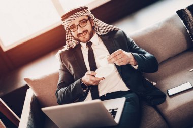 Dizüstü bilgisayar kullanarak bir iş adamı. Arap iş adamı. Siyah takım elbise giyen adam. Deneyimli girişimci. Office, başarılı genç adam adet eser bulunmaktadır. Arap gözlük. Kanepenin üstüne yalan. kahve holding