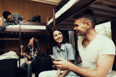 Hostel genç insanlar için. Seyahat arkadaşlarım. Hostel küçük odada. Birlikte vakit. ranza yatak odasında. gülümseyen insanlar. İletişim. Koltuk işgal. Birbirlerine bakıyorlar. telefon tutarak
