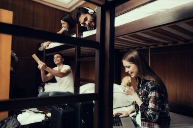 Hostel genç insanlar için. Seyahat arkadaşlarım. Hostel küçük odada. Birlikte vakit. ranza yatak odasında. gülümseyen insanlar. İletişim. Otur ve yatağa uzan. Laptop arıyorum. kız yiyor. peeps