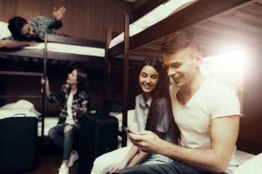 Hostel genç insanlar için. Seyahat arkadaşlarım. Hostel küçük odada. Birlikte vakit. ranza yatak odasında. gülümseyen insanlar. İletişim. telefona bak. Koltuk işgal. Otur ve yatağa yalan
