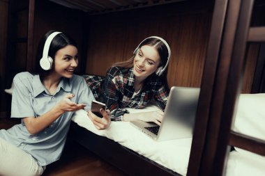 Hostel genç insanlar için. Seyahat arkadaşlarım. Hostel küçük odada. Birlikte vakit. ranza yatak. gülümseyen kadın. telefon arıyor. kızlar yatakta. müzik dinlemek. katta oturan
