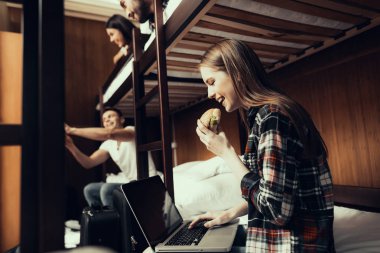 Hostel genç insanlar için. Seyahat arkadaşlarım. Hostel küçük odada. Birlikte vakit. ranza yatak odasında. gülümseyen insanlar. İletişim. Otur ve yatağa uzan. Laptop arıyorum. kız yiyor