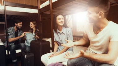 Hostel genç insanlar için. Seyahat arkadaşlarım. Hostel küçük odada. Birlikte vakit. Birbirlerine bakıyorlar. ranza yatak odasında. gülümseyen insanlar. İletişim. Bagaj açmak. yataklar üzerinde oturmak