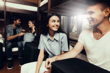 Hostel genç insanlar için. Seyahat arkadaşlarım. Hostel küçük odada. Birlikte vakit. Birbirlerine bakıyorlar. ranza yatak odasında. gülümseyen insanlar. İletişim. Bagaj açmak. yataklar üzerinde oturmak