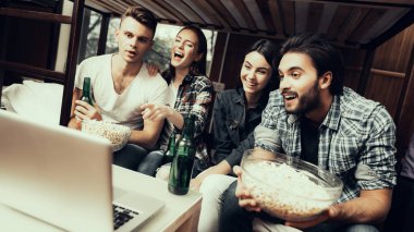 Hostel genç insanlar için. En iyi oynayan arkadaşlar. Hostel küçük odada. Birlikte vakit. gülümseyen insanlar. Yatağın üstüne oturan arkadaşlar. birlikte film izlerken. patlamış mısır yemek. yan fotoğraf.