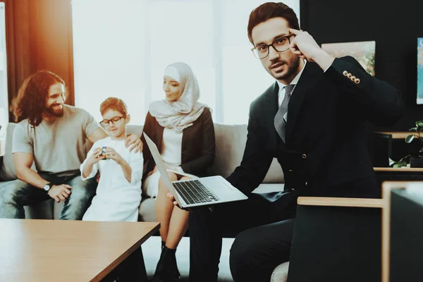 Arab Family at Reception in Psychotherapist Office. Family is Father, Mother and Son. Psychotherapist is Caucasian Man. Boy is Holding Rubik\'s Cube. Doctor is Holding Laptop and Pointing on His Head.