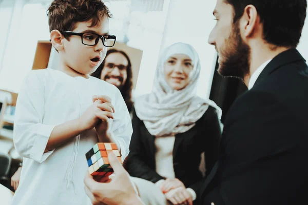 Arab Family at Reception in Psychotherapist. Happy Family is Father, Mother and Son. Psychotherapist is Caucasian Man. Psychologist is Shows Rubik\'s Cube to Boy. Boy is Surprised. Psychologist Office.