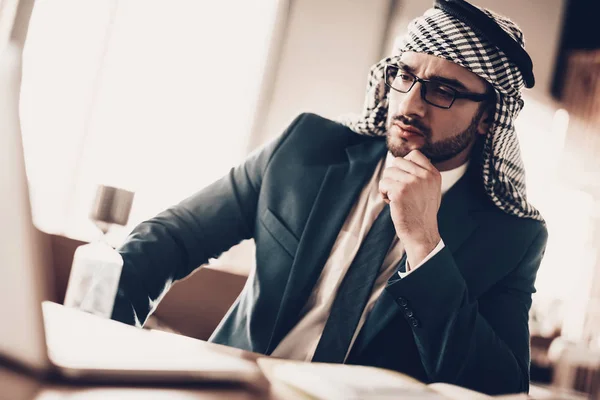 アラブのビジネスマン 黒のスーツを着ている男 経験豊富な起業家 アラビア人の成功した若い男の肖像メガネでアラブ ノート パソコンを探しています テーブルで作業します ピアリングの男 クローズ アップ — ストック写真
