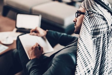 Masa üstünde Laptop. Arap iş adamı. Siyah takım elbise giyen adam. Deneyimli girişimci. Office, başarılı genç adam adet eser bulunmaktadır. Arap gözlük. Adam bakan ve Not defteri yazın. yakın çekim