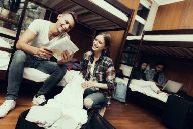 Hostel genç insanlar için. Seyahat arkadaşlarım. Hostel küçük odada. Birlikte vakit. ranza yatak odasında. Gülümseyen insanlar... Yatağa otur. çanta paketini açmalısınız. harita tutarak. harita üzerinde birlikte arıyorsunuz