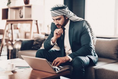 İşadamı Laptop kullanıyor. İş adamı. Siyah takım elbiseli adam. Deneyimli bir girişimci. Başarılı genç adam. Ofiste çalış. Düşünceli Adam. Grafikler masada. Bir fincan kahve..