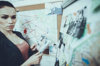 Dedektif Özel Dedektiflik Bürosu 'nda çalışıyor. Dedektif, güzel beyaz bir kadın. Kadın, elinde fotoğraflar tutuyor. Bayan Ceket Giyiyor. Bayan ciddi ve bir şeyler düşünüyor..