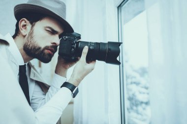 Dedektif Özel Dedektiflik Bürosu 'nda çalışıyor. Dedektif Kafkasyalı bir genç. Adam Pencere 'den fotoğraf çekiyor. Şahıs Profesyonel Kamera 'yı kullanıyor. Kişi Pelerin ve Şapka Giyer.
