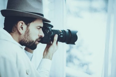 Dedektif Özel Dedektiflik Bürosu 'nda çalışıyor. Dedektif Kafkasyalı bir genç. Adam Pencere 'den fotoğraf çekiyor. Şahıs Profesyonel Kamera 'yı kullanıyor. Kişi Pelerin ve Şapka Giyiyor.