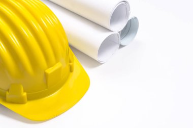 Sarı kask ve haddelenmiş kağıt ve beyaz arka plan üzerinde planları.