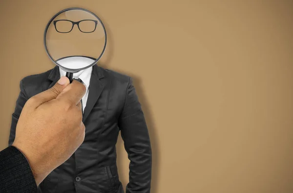 The concept, businessman searches, hand holding a magnifying glass to the black suit isolated with clipping path.