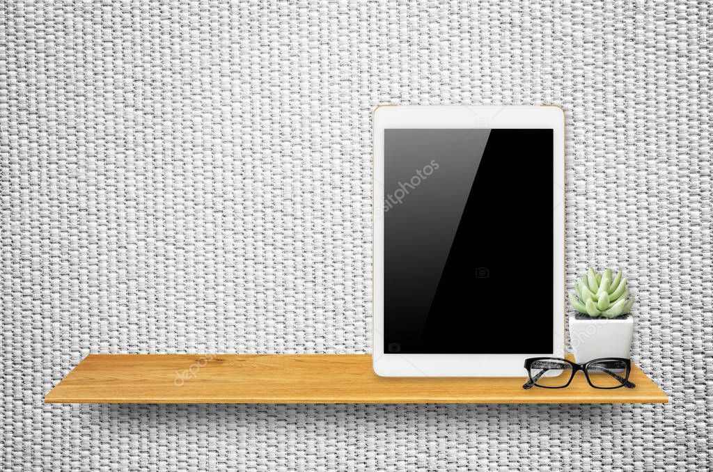 Digital tablet computer with isolated screen with clipping path on bookshelf in the wall.