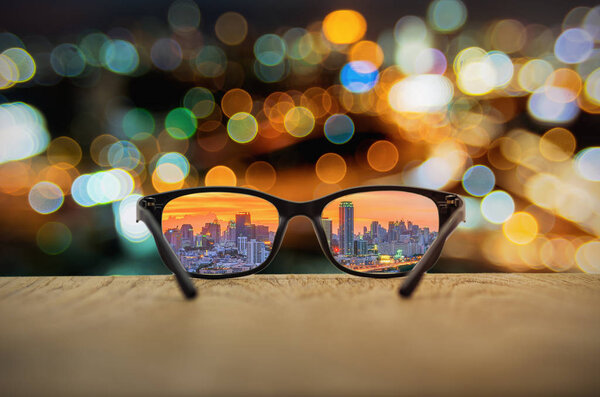 Clear cityscape focused in glasses lenses with blurred cityscape background.