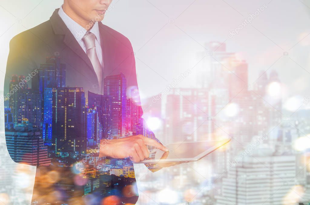 Double exposure of city and business man using digital tablet.