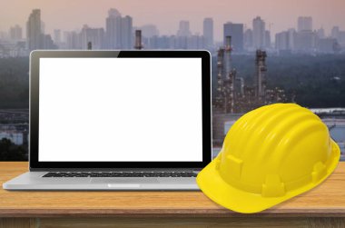 Sarı kask ve sanayi arka plan, ekran üzerinde boş masa üstünde laptop.