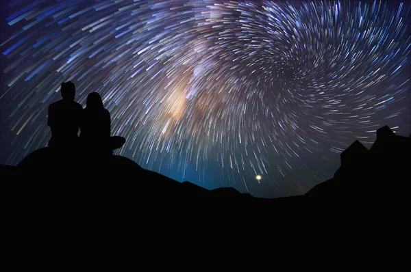 Silhouette of a couple watching the stars at night, long speed exposture.