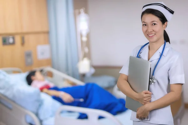 Asian nurse holding notebook with background blur patient room.