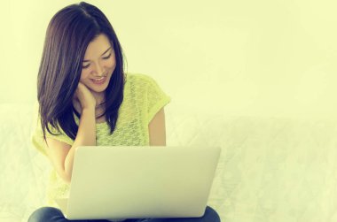 İç, dizüstü bilgisayar kullanarak mutlu genç güzel Asyalı kadın. Vintage tarzı.