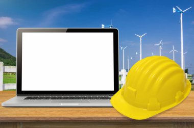 Sarı kask ve sanayi arka plan, ekran üzerinde boş masa üstünde laptop.