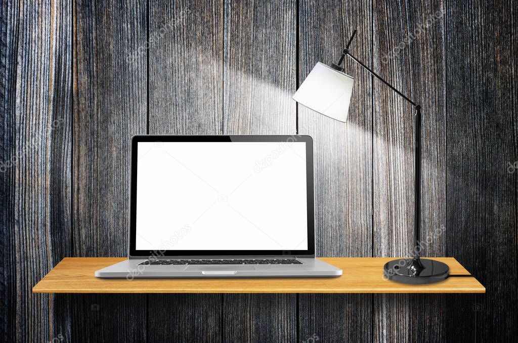 Laptop computer with blank screen and lamps on desk in the wall.