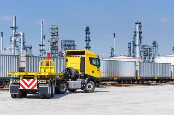Trucks and containers on rail against the backdrop of the refinery, Industrial and transportation concept.