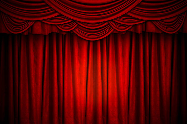 Красный закрытый занавес со светлыми пятнами на сцене на заднем плане
.