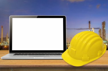 Sarı kask ve sanayi arka plan, ekran üzerinde boş masa üstünde laptop.