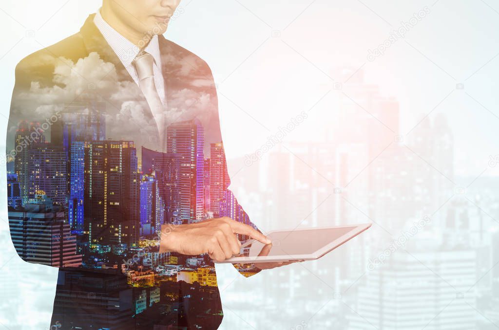 Double exposure of city and business man using digital tablet.