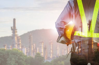 Double exposure of engineer behind with overload tool holding yellow helmet for safety of the workers, Blurred Oil refinery background. clipart