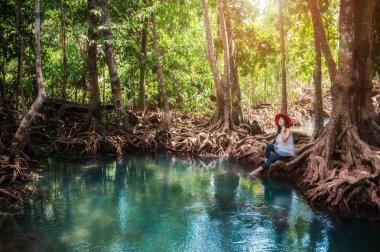 Ağaç üzerinde oturan bir hipster Bayan kökleri, Tha pom mangrov orman, güzel Emerald havuzda mangrov orman, Krabi, Tayland. 