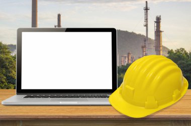Sarı kask ve sanayi arka plan, ekran üzerinde boş masa üstünde laptop.