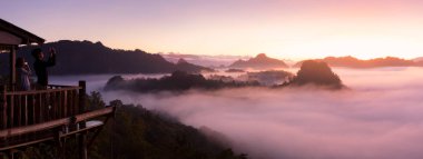 Mae Hong Son - 11 Ocak: Erkek ve dişi seyahat etmek onların akıllı telefonlar yükselterek, kayıt gündoğumu ve buğu Ahşap Teras Baan Jabo bakış açısı 11 Ocak 2018 üzerinde Mae Hong Son, Thailand.