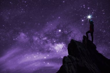 Siluet dağcı veya backpacker, o yıldız dik başını düzenlenen. Kayalık dağ tepe samanyolu galaksi, yıldız ve Uzay tozu evren, başarı, lider kavramı karşı üzerinde duran.
