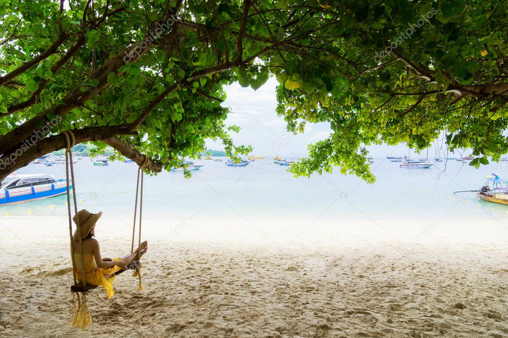 Traveler Asian woman in bikini relaxing on wooden swing and looking at sea, Phi Phi Island, Andaman sea, Krabi, Travel in Thailand, Summer holiday and vacation travel trip.